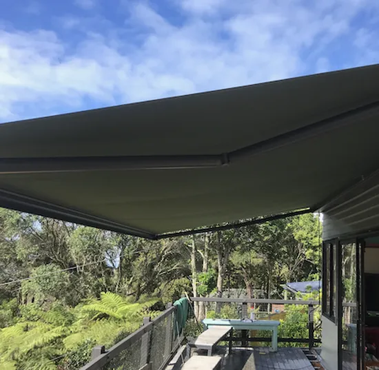 Retractable awning shading outdoor bush deck in New Zealand with wooden table setting