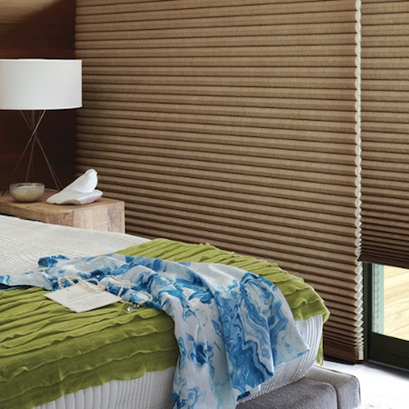 Honeycomb blinds in warm brown fabric installed in a modern bedroom, providing thermal insulation and a sleek contemporary look.