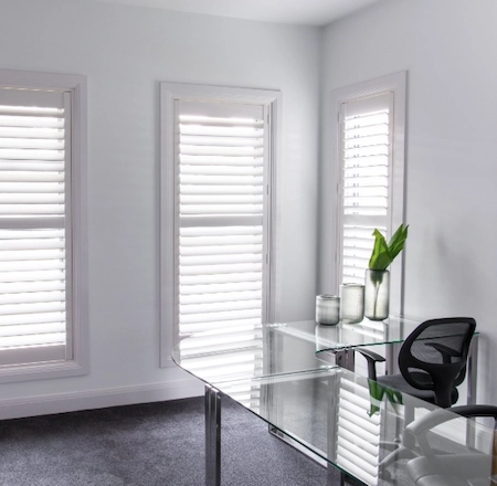White plantation shutters in a home office to control glare and light